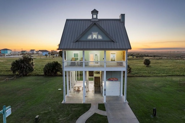 view of front of house with a porch, a yard, a balcony, and a garage