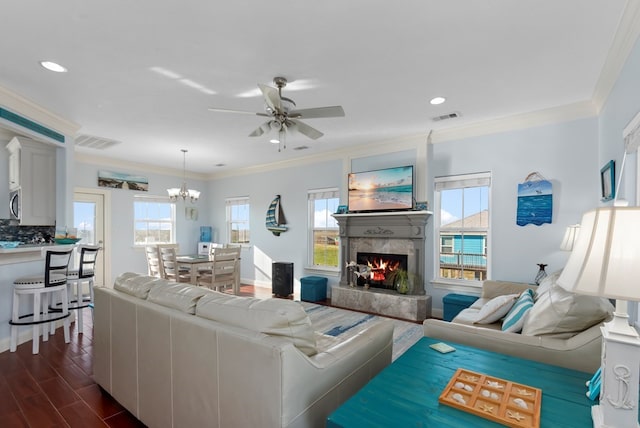 living room featuring dark hardwood / wood-style floors, ceiling fan with notable chandelier, crown molding, and a high end fireplace