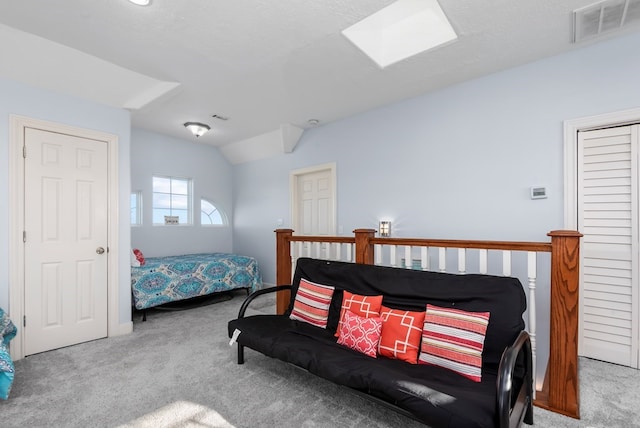 carpeted bedroom featuring lofted ceiling with skylight and a textured ceiling