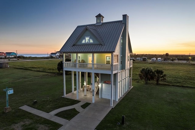 exterior space with a lawn, a balcony, a water view, and a garage