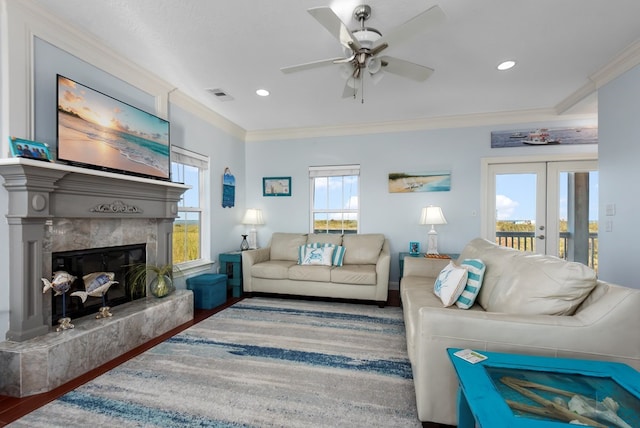 living room with hardwood / wood-style floors, plenty of natural light, ornamental molding, and a fireplace