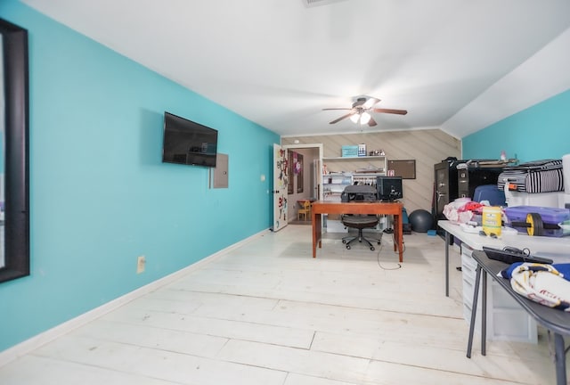 office area featuring light wood finished floors, baseboards, a ceiling fan, vaulted ceiling, and wood walls