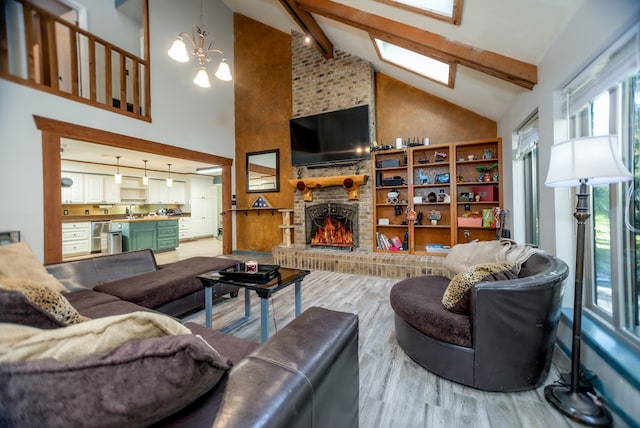 living area with a brick fireplace, a chandelier, beamed ceiling, and wood finished floors