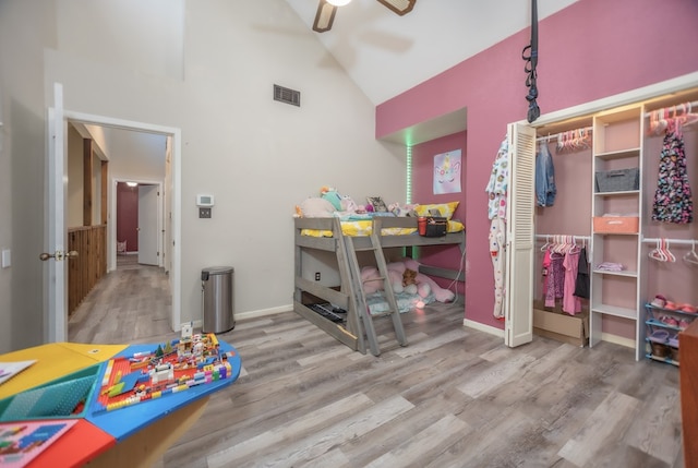 bedroom with high vaulted ceiling, visible vents, baseboards, and wood finished floors