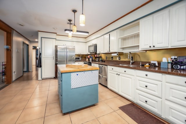 kitchen featuring a center island, stainless steel appliances, wooden counters, white cabinetry, and a sink