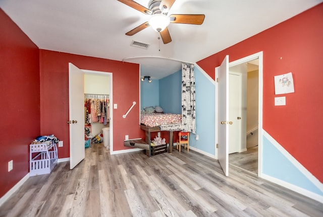 interior space featuring a ceiling fan, wood finished floors, visible vents, and baseboards