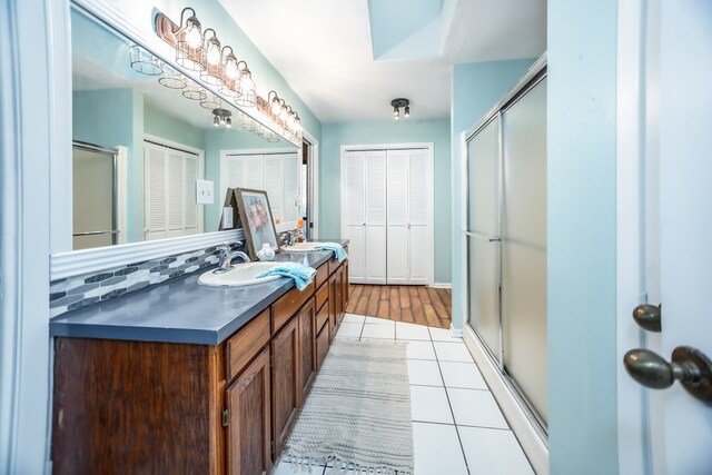 full bathroom with tile patterned flooring, a closet, an enclosed shower, and a sink