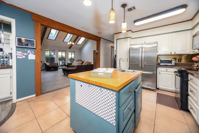 kitchen with light tile patterned floors, electric range, wood counters, stainless steel refrigerator, and pendant lighting