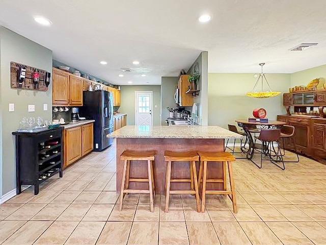 341 Red Wolf Ln, Brookeland, TX 75931 - kitchen with black fridge with ice dispenser, light tile patterned floors, a breakfast bar, a peninsula, and recessed lighting