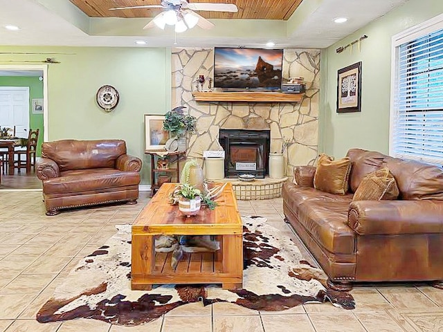 341 Red Wolf Ln, Brookeland, TX 75931 - tiled living room featuring a tray ceiling, ceiling fan, wood ceiling, a stone fireplace, and recessed lighting