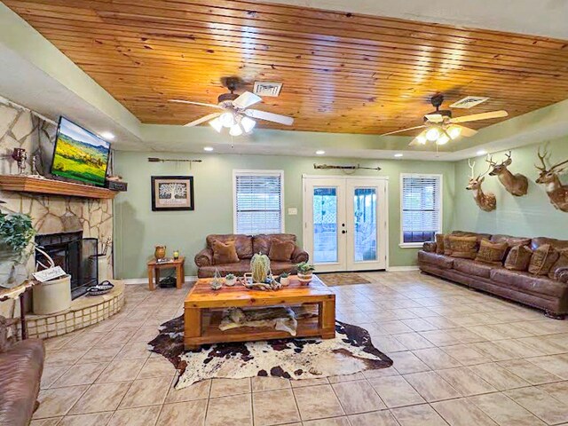 341 Red Wolf Ln, Brookeland, TX 75931 - living area featuring a tray ceiling, wooden ceiling, ceiling fan, tile patterned floors, and a stone fireplace