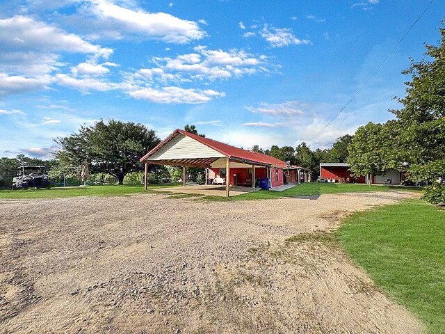 341 Red Wolf Ln, Brookeland, TX 75931 - view of community with dirt driveway, a carport, and a lawn