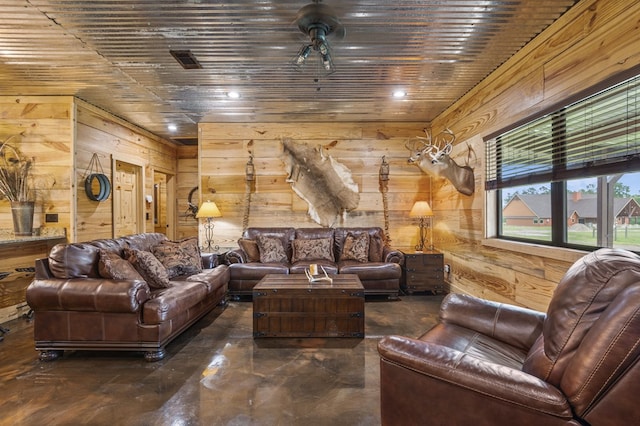 living room with ceiling fan and wood walls