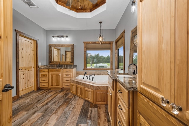 bathroom with a bathing tub, vanity, a raised ceiling, and wood-type flooring