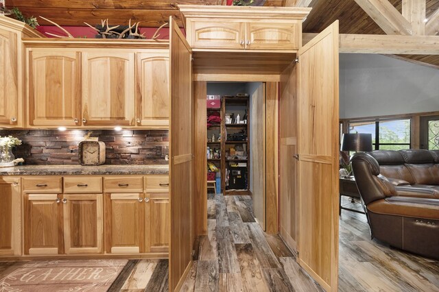 interior space with light brown cabinets, wood-type flooring, and tasteful backsplash