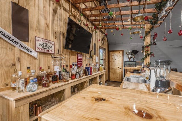 bar featuring butcher block countertops, sink, and wooden walls