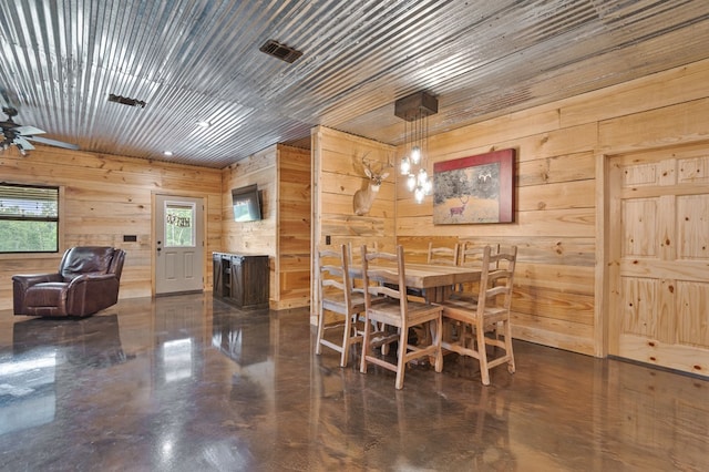 dining room with wood walls and an inviting chandelier