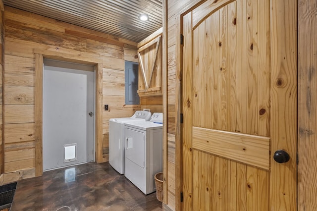 laundry room featuring washing machine and clothes dryer, electric panel, cabinets, and wood walls