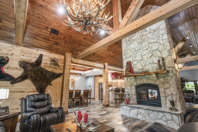 living room with a stone fireplace, hardwood / wood-style flooring, beam ceiling, wood ceiling, and a chandelier