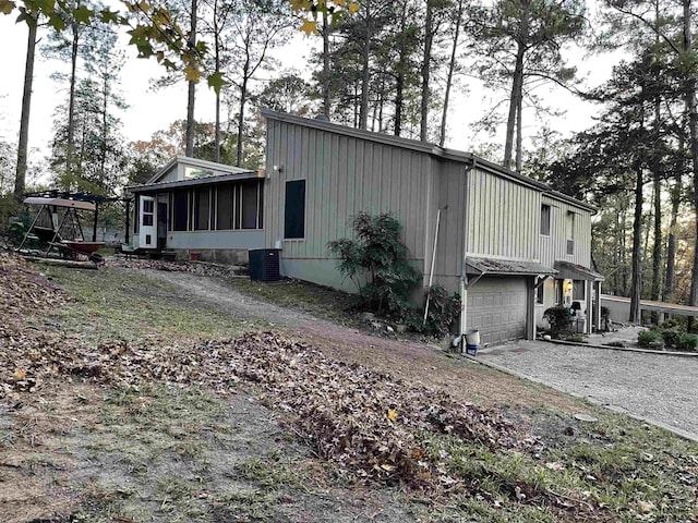 view of property exterior featuring central air condition unit, a garage, and a sunroom