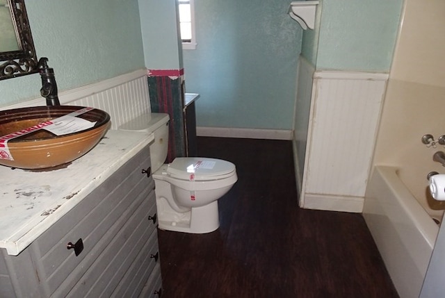 bathroom featuring hardwood / wood-style flooring, vanity, toilet, and a tub