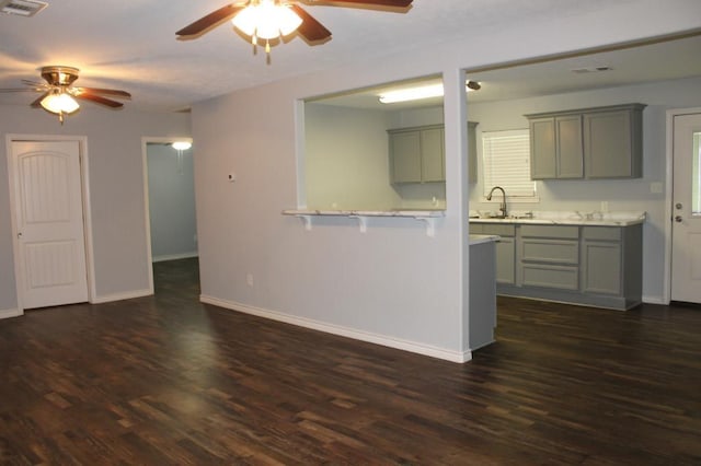 kitchen with kitchen peninsula, gray cabinets, dark hardwood / wood-style flooring, and sink