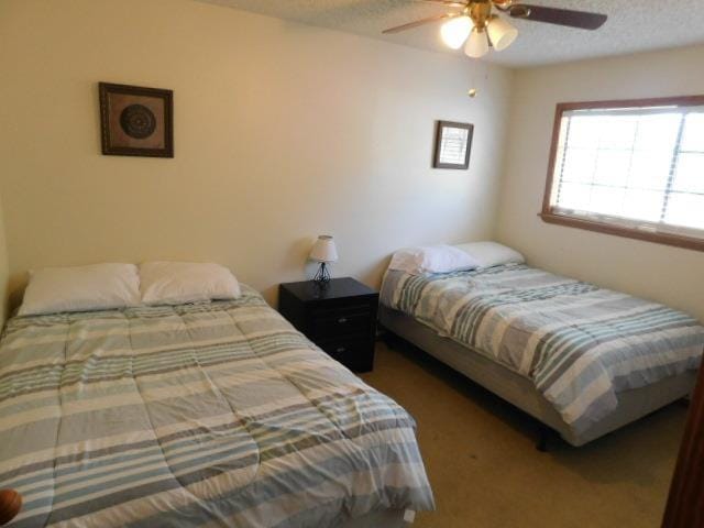 carpeted bedroom featuring ceiling fan and a textured ceiling