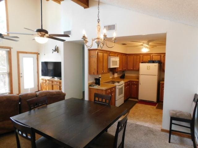 dining space with beam ceiling, high vaulted ceiling, light colored carpet, and ceiling fan with notable chandelier