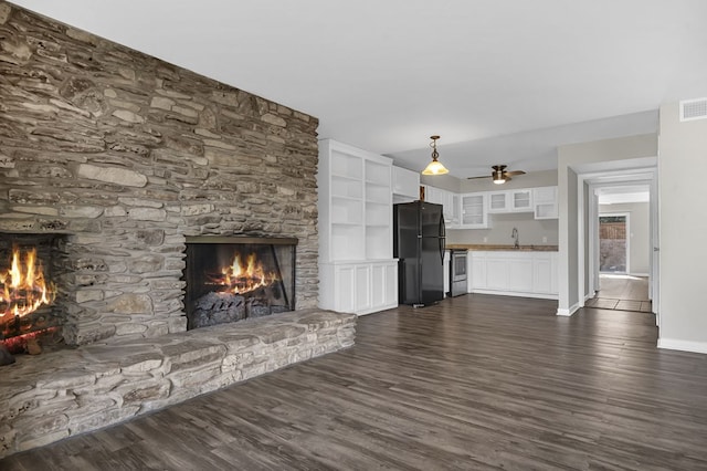 unfurnished living room with a fireplace, ceiling fan, dark wood-type flooring, and sink