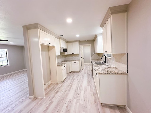 213 Crosstimbers St, Lufkin, TX 75904 - kitchen featuring a sink, white microwave, light wood-style floors, light stone counters, and white cabinets