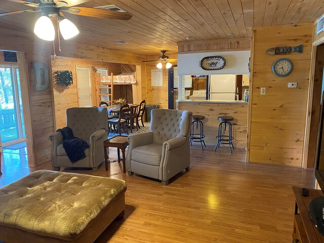 living room featuring light wood-type flooring, wood ceiling, and wood walls