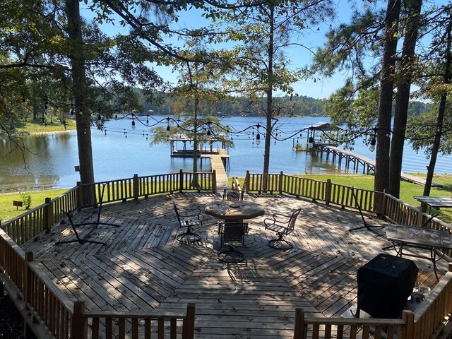 wooden terrace with a water view and a lawn