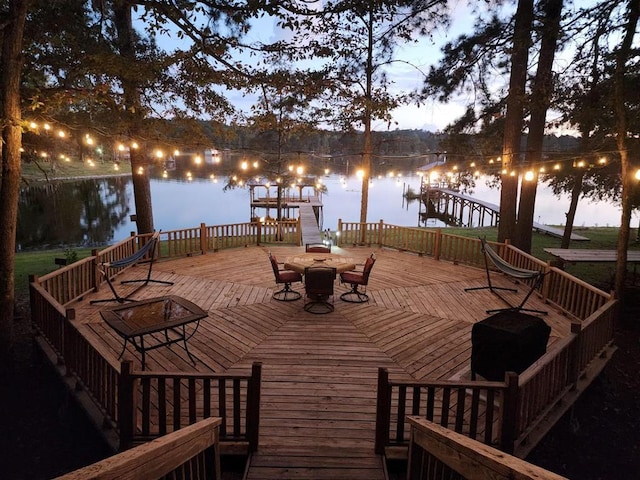 deck at dusk featuring a grill and a water view