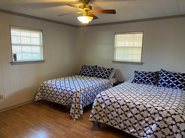 bedroom with hardwood / wood-style flooring, ceiling fan, and crown molding