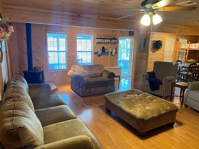 living room featuring a wood stove, wood walls, hardwood / wood-style floors, and wooden ceiling