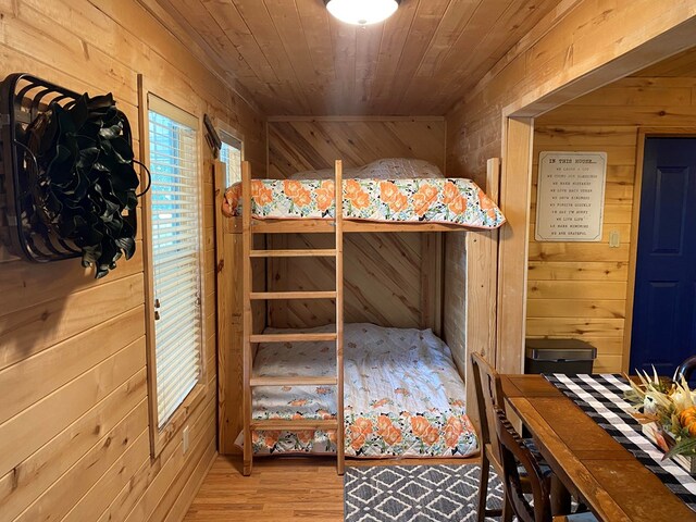 bedroom with hardwood / wood-style floors, wooden ceiling, and wooden walls