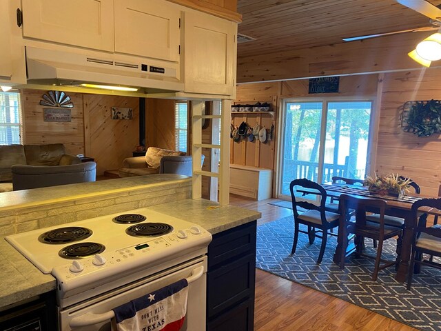 kitchen with wood-type flooring, white electric stove, and wood walls