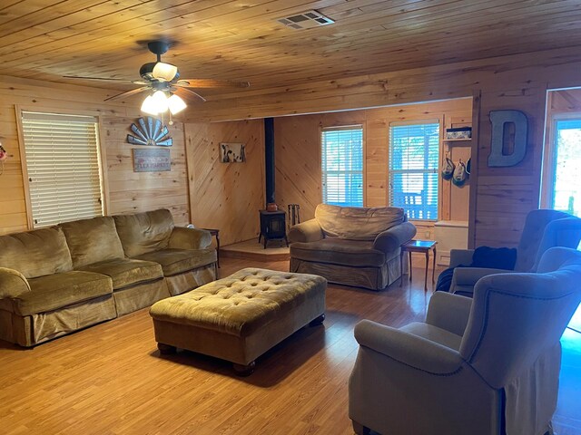 living room with hardwood / wood-style floors, a wood stove, wooden walls, and wood ceiling