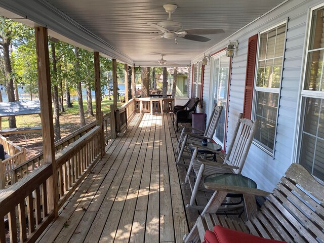 wooden deck featuring ceiling fan, a porch, and a water view