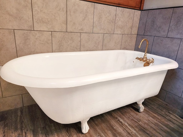 full bath featuring a freestanding tub, wood finished floors, and tile walls