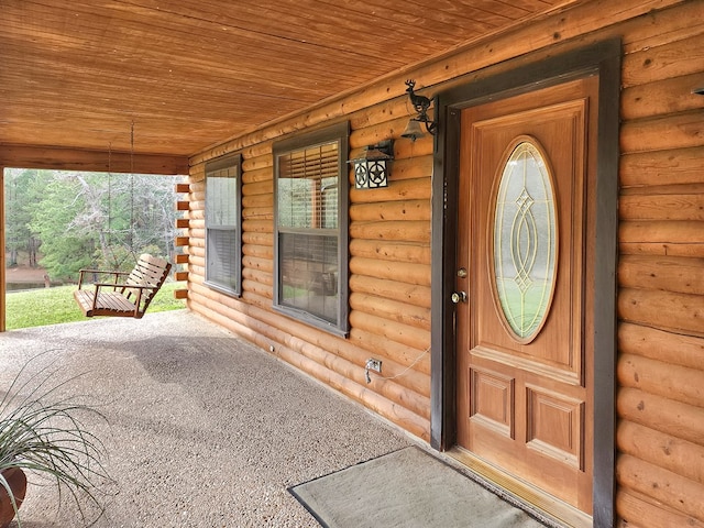 doorway to property with covered porch and log veneer siding