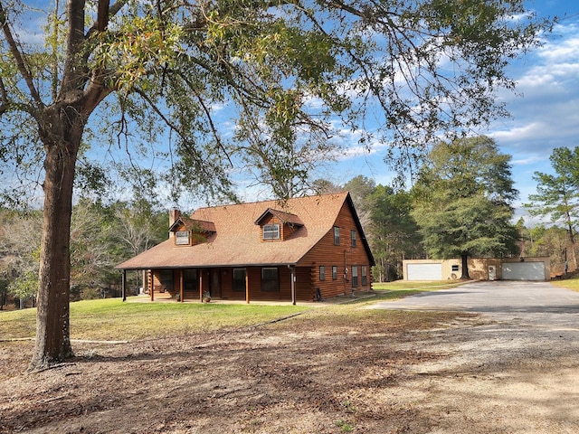 view of front of home featuring an outbuilding, a chimney, a front yard, and a garage