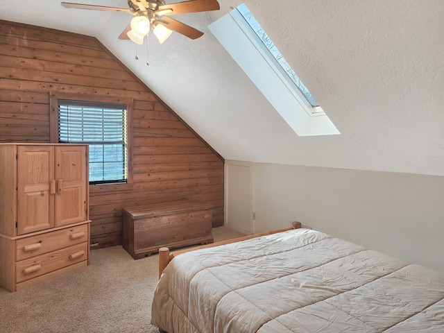 bedroom with vaulted ceiling with skylight, light colored carpet, ceiling fan, and a textured ceiling