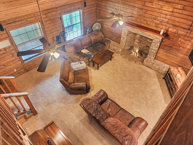 unfurnished living room with wooden walls, carpet, a fireplace, and ceiling fan