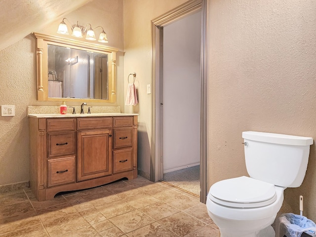 bathroom with a textured wall, vanity, and toilet