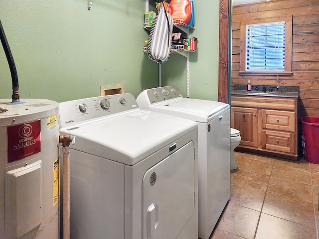 washroom with light tile patterned flooring, water heater, a sink, and separate washer and dryer