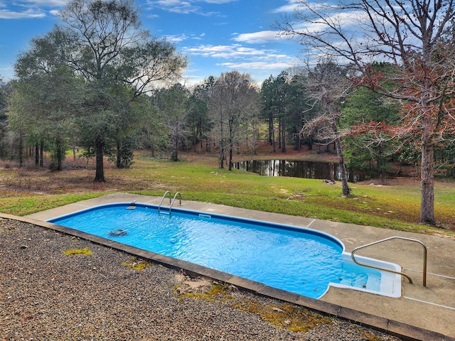 pool with a patio, a lawn, and a water view