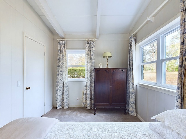 carpeted bedroom featuring multiple windows and beam ceiling