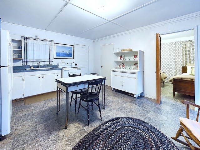 kitchen with white cabinetry, white fridge, and sink