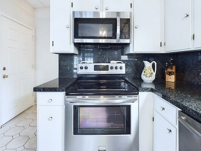 kitchen with tasteful backsplash, dark stone countertops, white cabinets, and appliances with stainless steel finishes